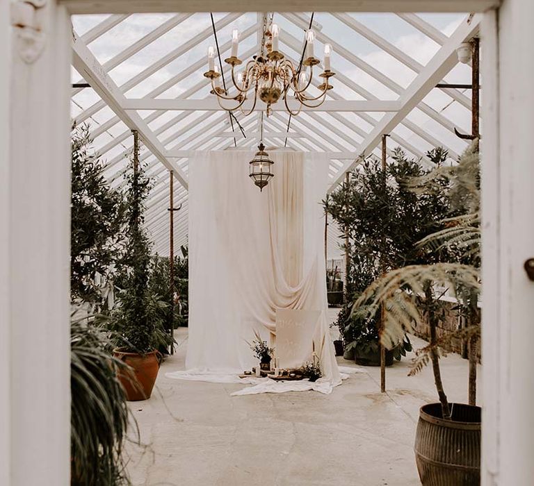 The glasshouse at The Gooseberry House decorated with drapes and a contemporary wedding welcome sign 