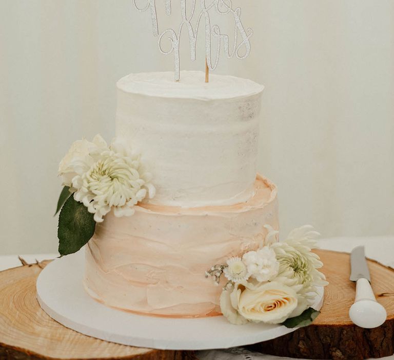 Two-tier wedding cake complete with peach & white frosting with glitter Mr & Mrs cake topper 