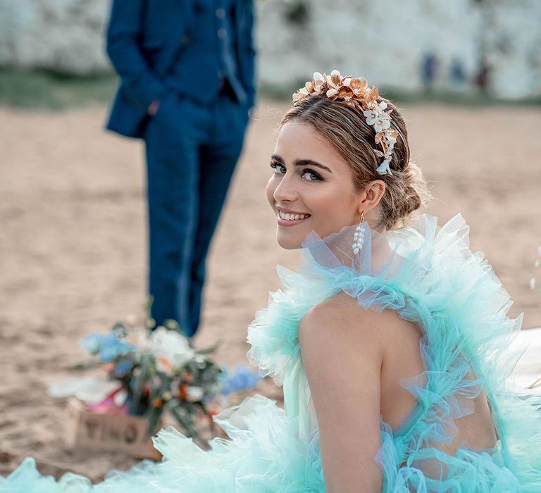 Bride in a mint green tulle wedding dress and gold headband at an intimate pastel beach elopement 