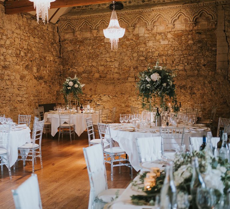 Elegant round white wedding tables with perspex bamboo chairs and white and green floral centrepieces for Notley Abbey wedding reception