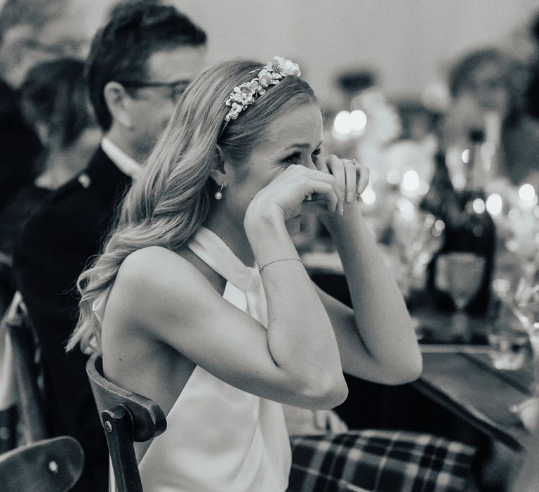 Bride in satin Halfpenny London wedding dress and bespoke Victoria Percival headband wipes away tears as groom makes speech at sperry tent wedding reception