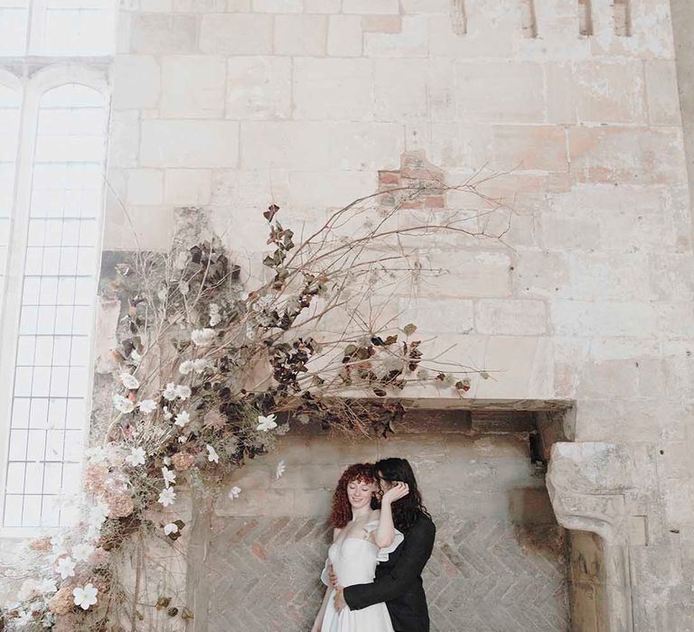 Bride and groom portrait in the giant fireplace at medieval wedding venue, Blackfriars Priory in Gloucestershire 