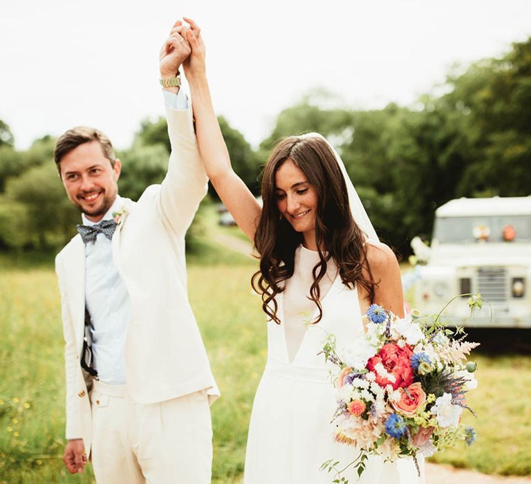 Bride & groom hold each others hands up on their wedding day outdoors