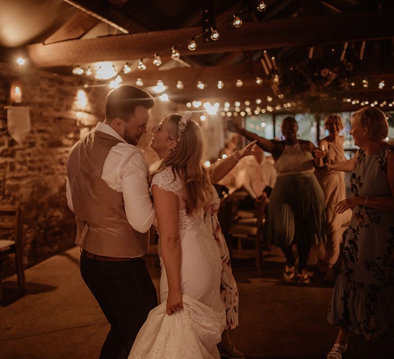 Bride and groom dancing at their Dewsall Court wedding reception with festoon lights 