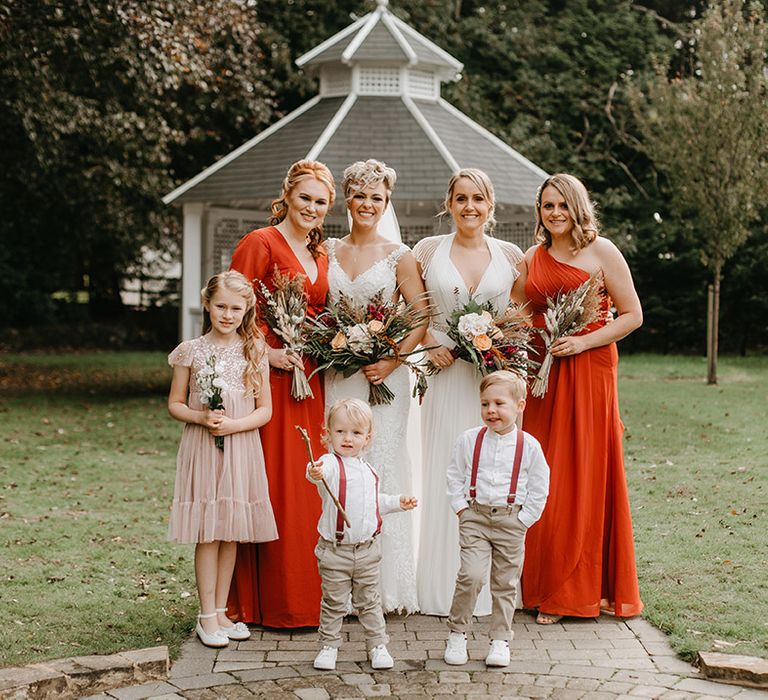 Brides stand with their bridesmaids, flower girls and page boys on their wedding day