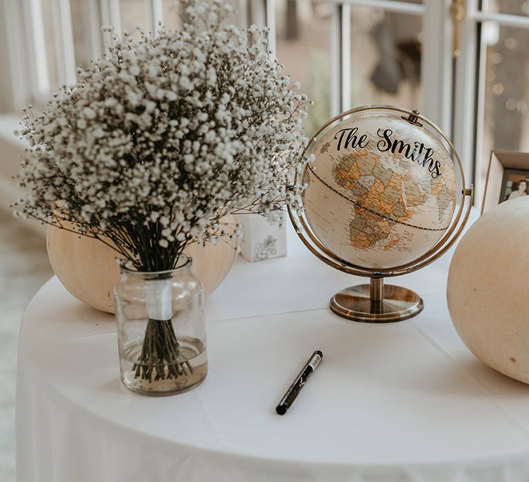 White pumpkins next to globe on white tablecloth 