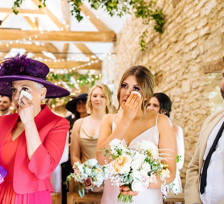 Emotional Mother Of The bride in a pink outfit and purple hat.