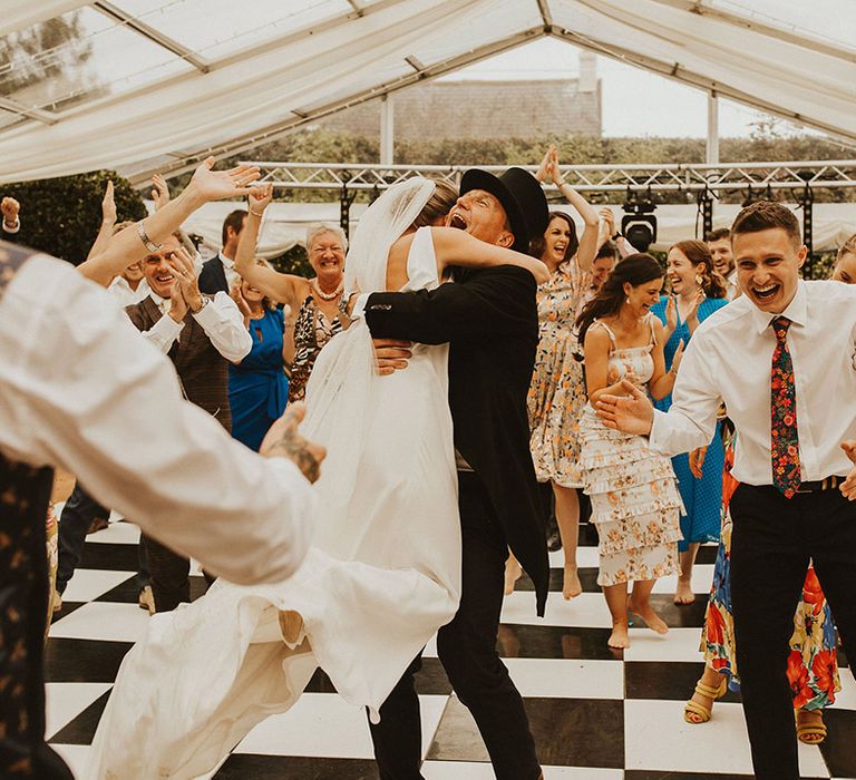 Bride embracing her father after a surprise flash mob dance 