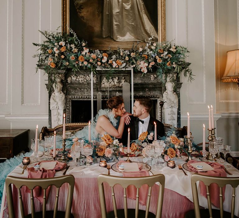 Intimate wedding reception in front of a fireplace with cafe au late, pink and peach wedding flowers and table decor 