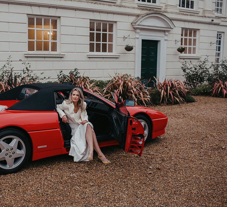 Bride sits in red Ferrari on her wedding day in front of Gosfield Hall