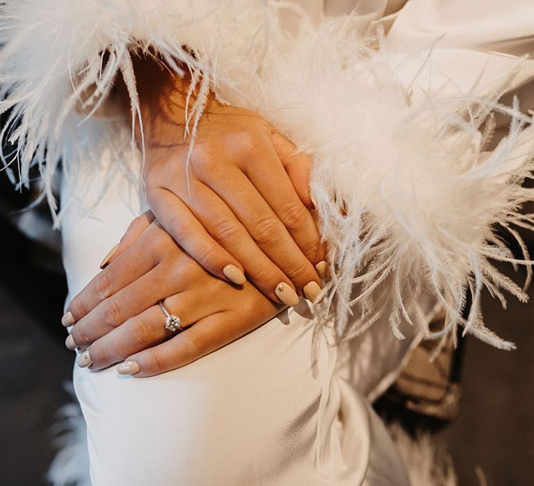 Nude and neutral nails with gold stars on accent nail with round diamond engagement ring and ostrich feather robe