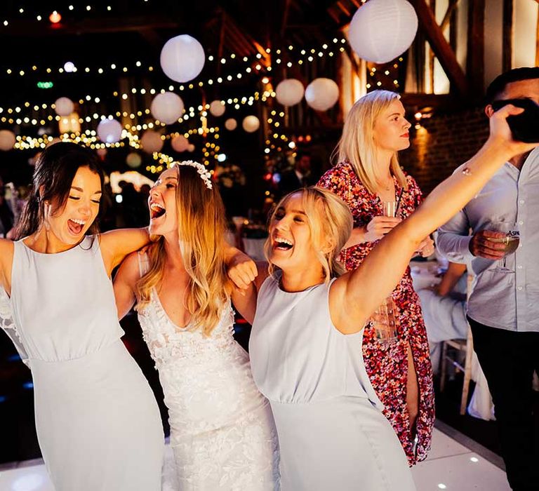 Bride partying with bridesmaids in grey high neck low back dresses at wedding reception