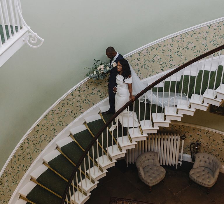 Bride and groom descend stairs together at Middleton Lodge wedding venue 