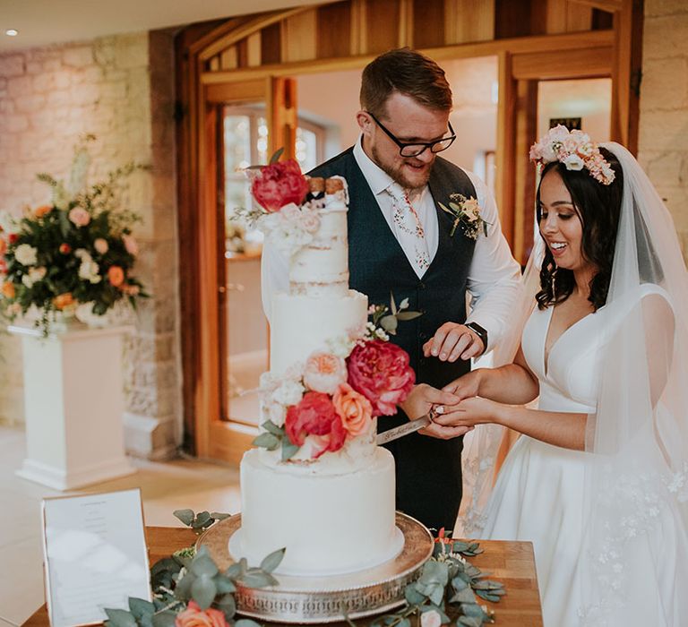 Bride and groom cut their four tier wedding cake together 