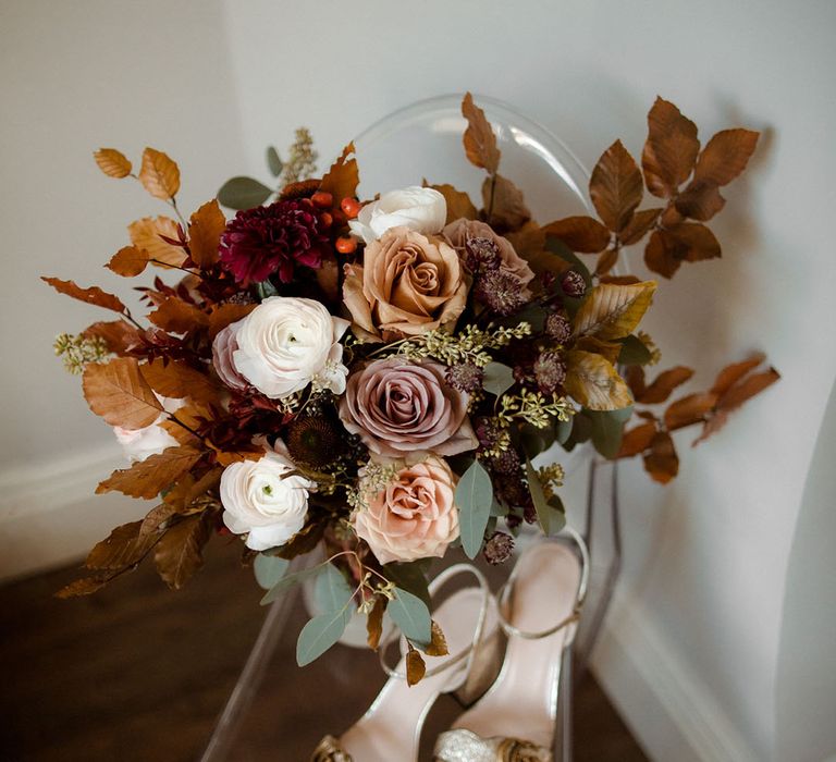 Autumnal coloured bridal bouquet next to gold Gucci sandal heels 