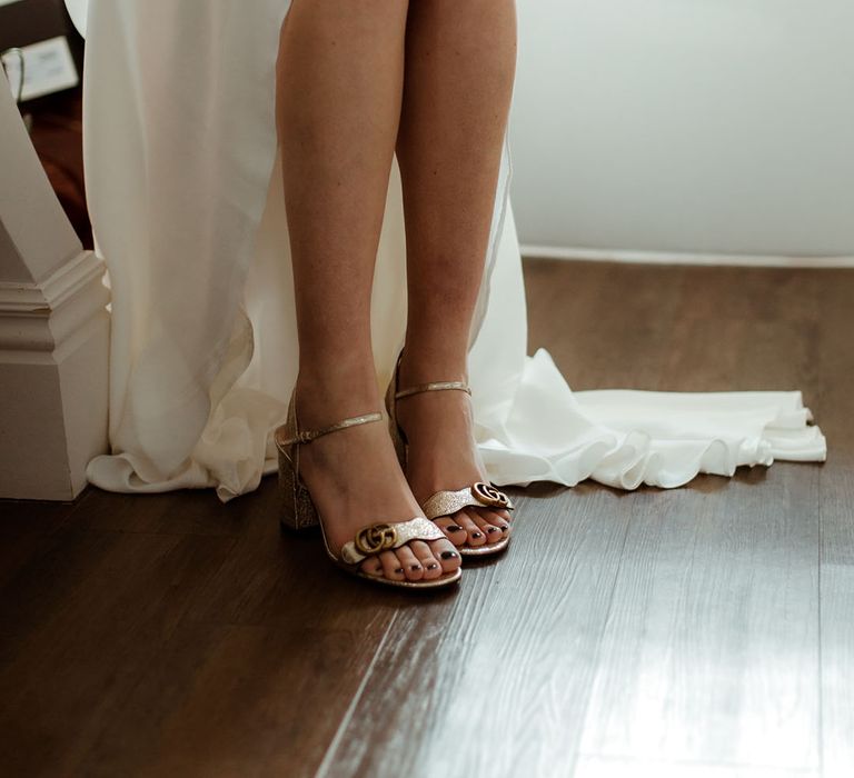 Bride wears gold Gucci heeled sandals complete with dark painted toe nails on her wedding day