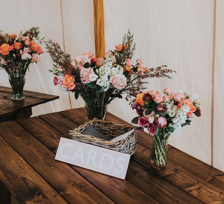 Wicker basket for cards from guests with pink and white flower bouquets 