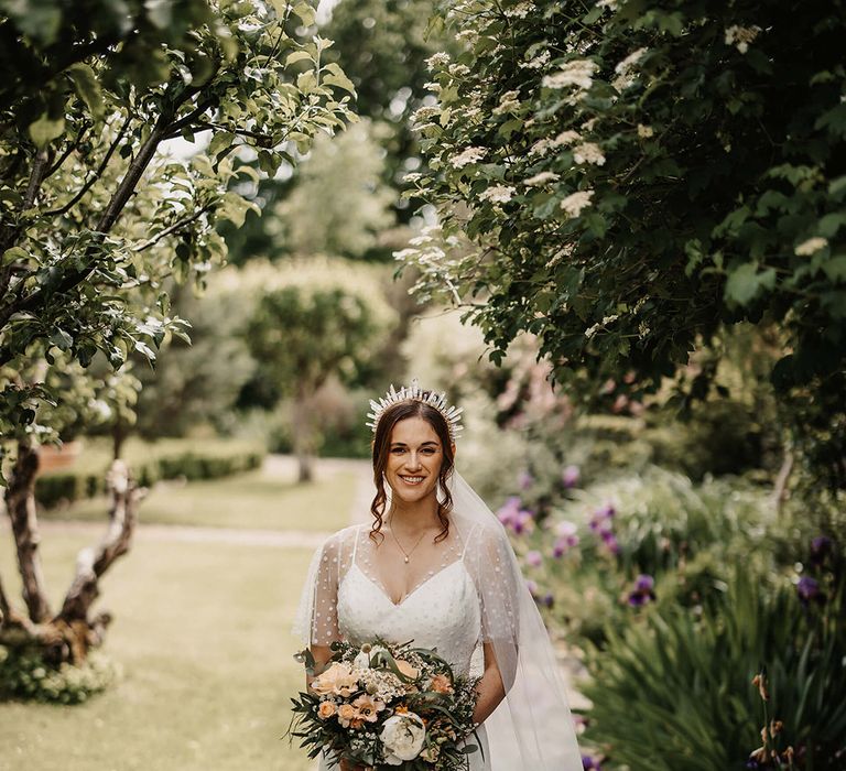 Bride in a dotted wedding dress from Love Spell with a quartz crystal crown and white and peach wedding bouquet