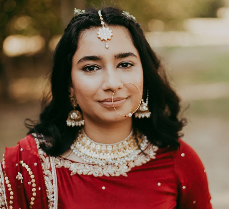 South East Asian bride wears her black hair in relaxed style complete with gold jewellery and hair piece 