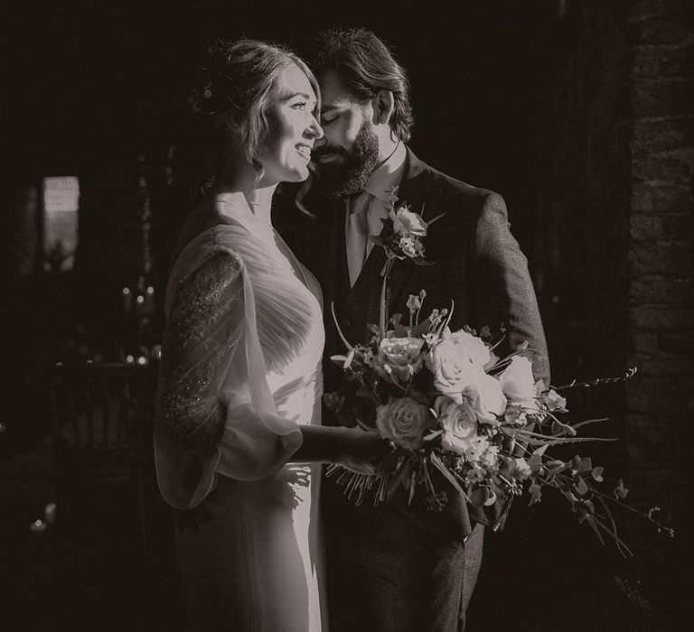 Bride in a sheer long sleeve wedding dress with the groom in a brown suit 