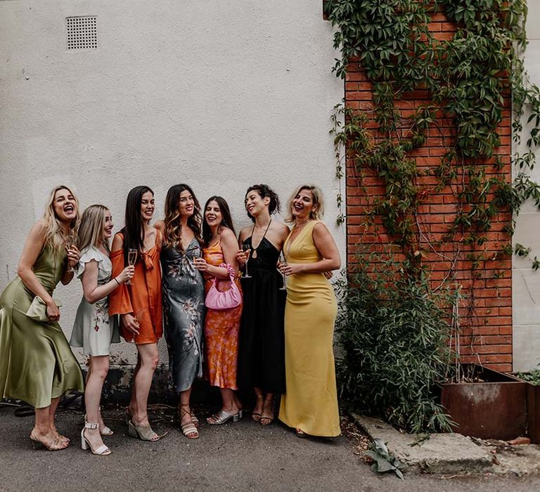 Bridal party in mismatching bridesmaid dresses posing and smiling at Hackney Studios