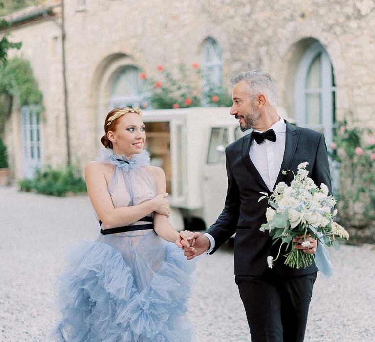 Bride wears full ruffled skirt pale blue wedding dress at destination wedding with groom in a tuxedo