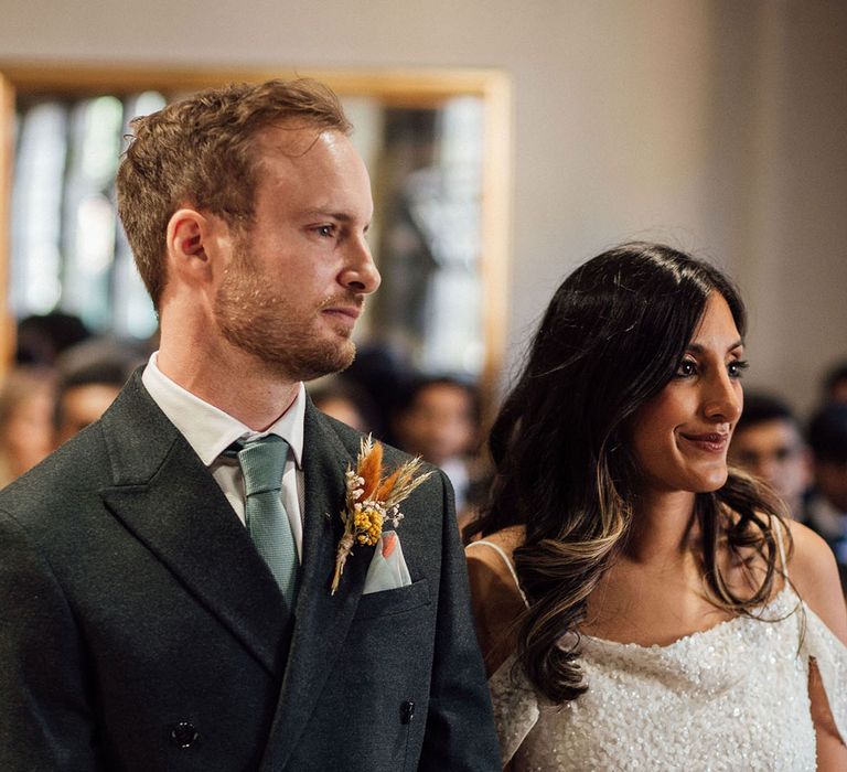 Bride in off-the-shoulder sequin embellished wedding dress stands beside her groom during civil ceremony 