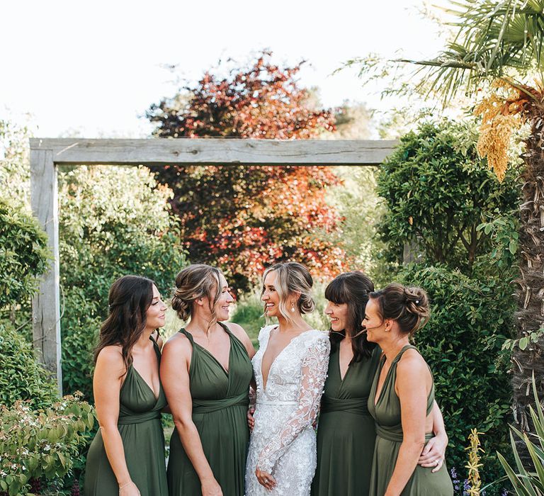 Bridesmaids in green bridesmaid dresses with the bride in a long sleeve sparkly wedding dress standing together for bridal party portraits at Le Petit Chateau