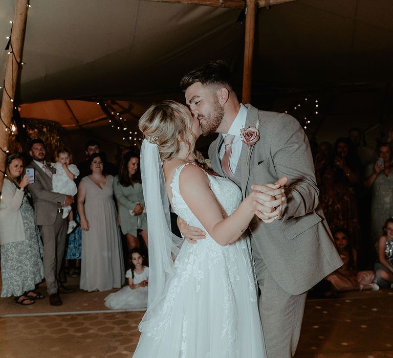 Bride & groom kiss during wedding reception in naked tipi 