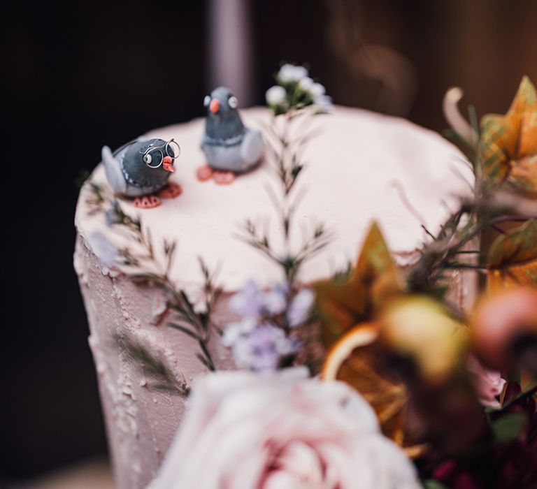 Fondant pigeon wedding cake toppers on top of the pale pink iced wedding cake to represent the couple's mascot 