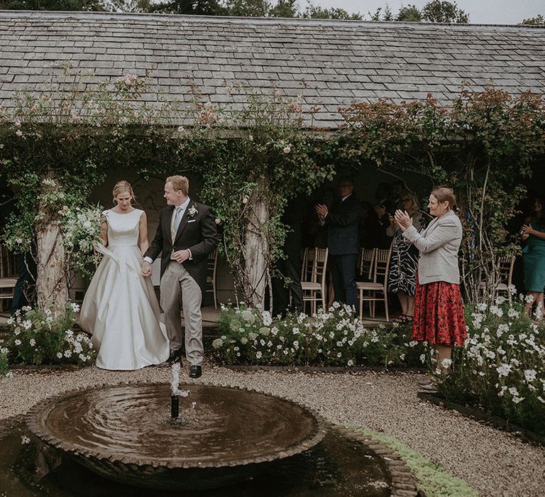 The bride and groom walk out from the sheltered wedding ceremony room for traditional and classic wedding day 