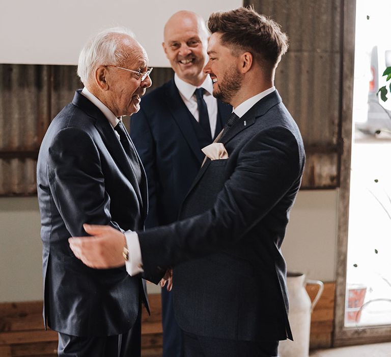 Groom in navy suit with the grandad in navy suit having a special moment together before the ceremony 