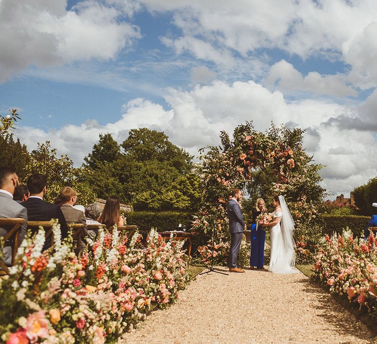 Romantic outdoor wedding at The Four Seasons in Hampshire with pink and white aisle flowers and floral arch decoration 