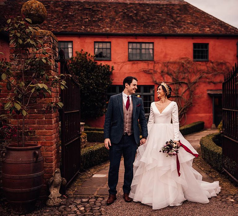 Groom in three piece blue suit with the bride in a long sleeve traditional wedding dress with ruffle wedding skirt 