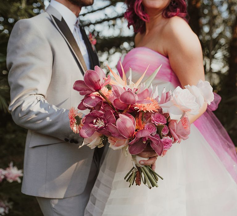 bride in a strapless wedding dress holding a bright pink orchid wedding bouquet