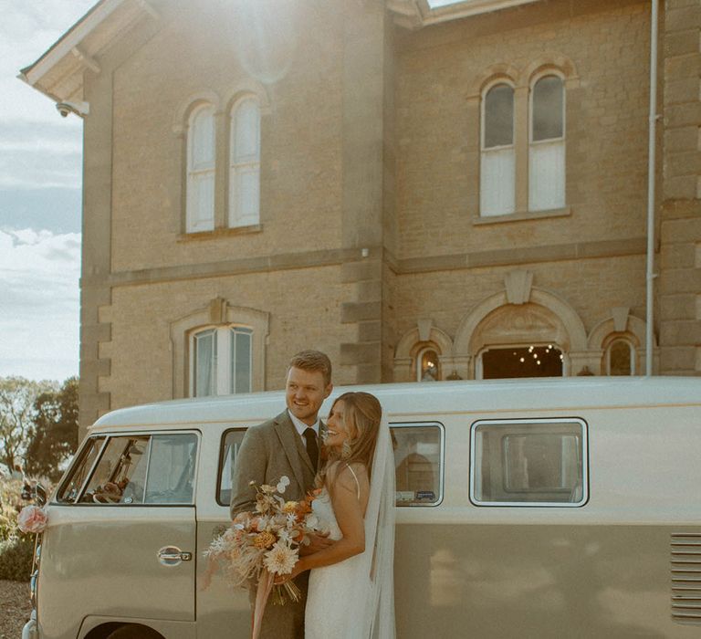 St Tewdrics House Chepstow wedding in Wales with the bride in a lace gown and groom in beige grey suit in front of vintage camper van 