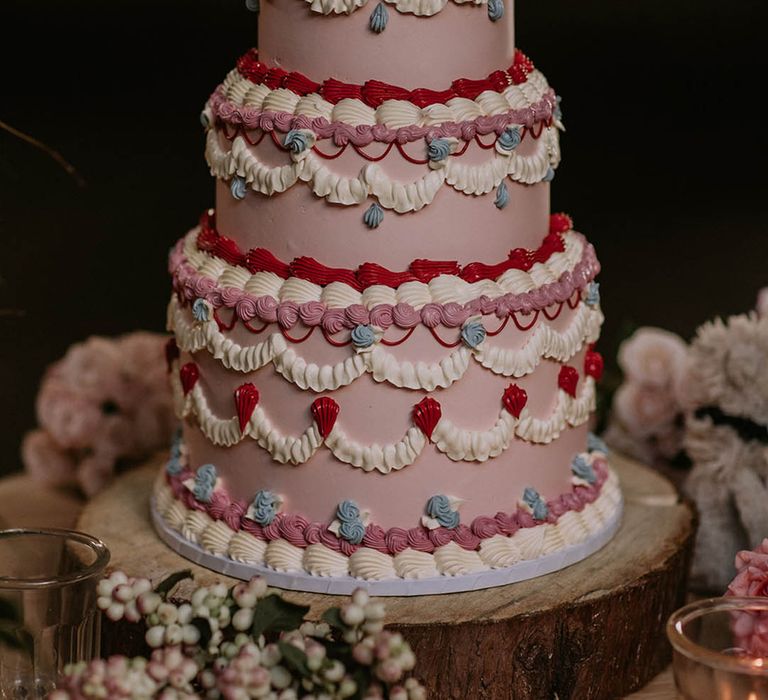 Huge three tier pink wedding cake with white, red, and blue piping for classic black tie wedding 