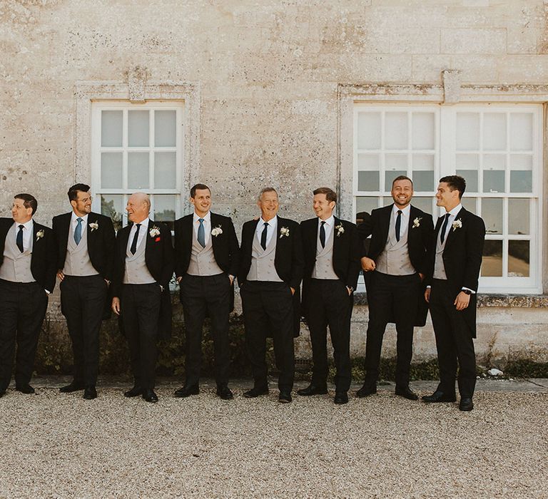 Groom and groomsmen in matching morning suits with pinstriped trousers and light blue ties 