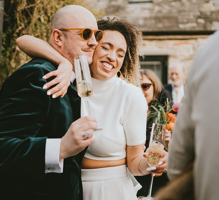 The bride and bridesman have some wedding drinks together as they embrace each other 