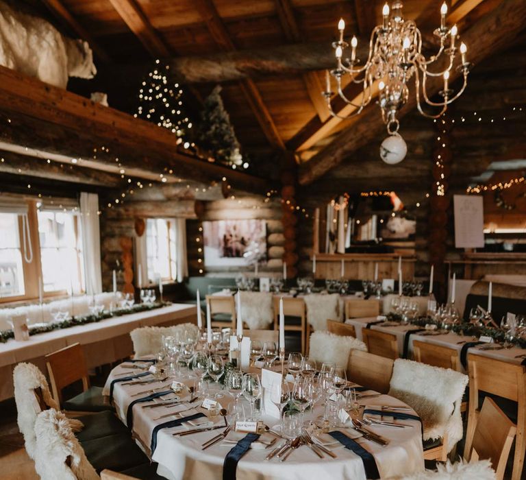 Classic wedding tablescape with forest green napkins, white wedding tablecloth, white tapered candles and minimalistic wedding stationery and menus at La Cabane Des Praz wedding venue