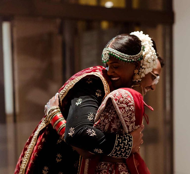 Groom in deep blue sherwani at Inner Temple Hall embracing bride in red and gold bridal lehenga 