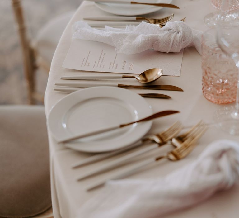 Classic gold, pink, and white wedding table decorations with white plates and menus 