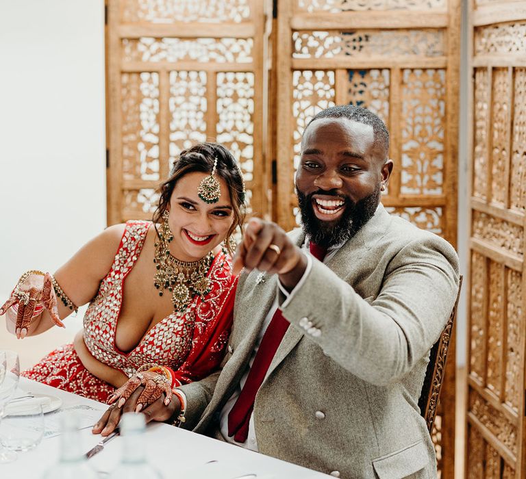 The bride and groom sit together on a sweetheart table enjoying their wedding breakfast together 