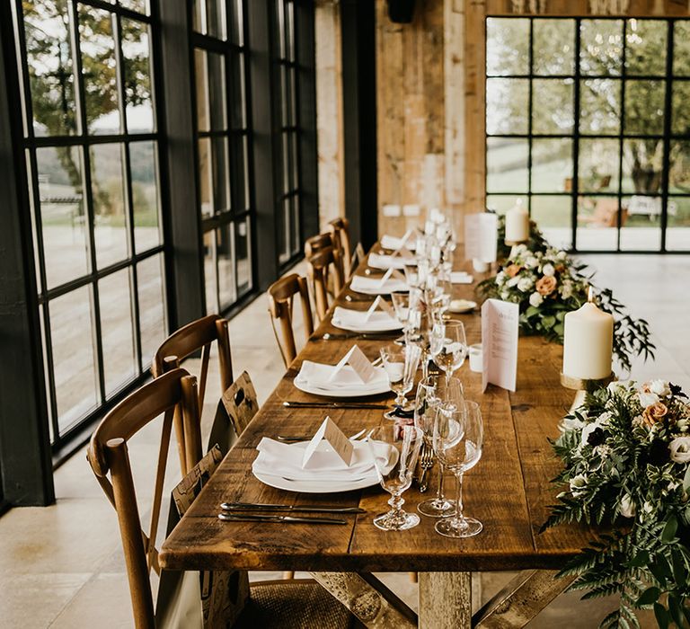 Wedding top table decorated with natural wedding flowers and ivory pillar candles 