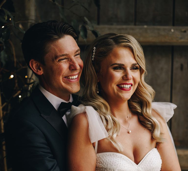 Bride wearing sparkly corset bodice wedding dress with diamanté sparkly hair clip with the groom in black tuxedo 