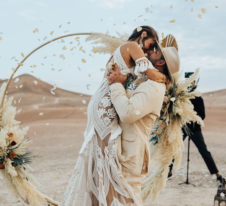 Romantic confetti wedding photo with bride leaping into the groom's arms for a kiss 