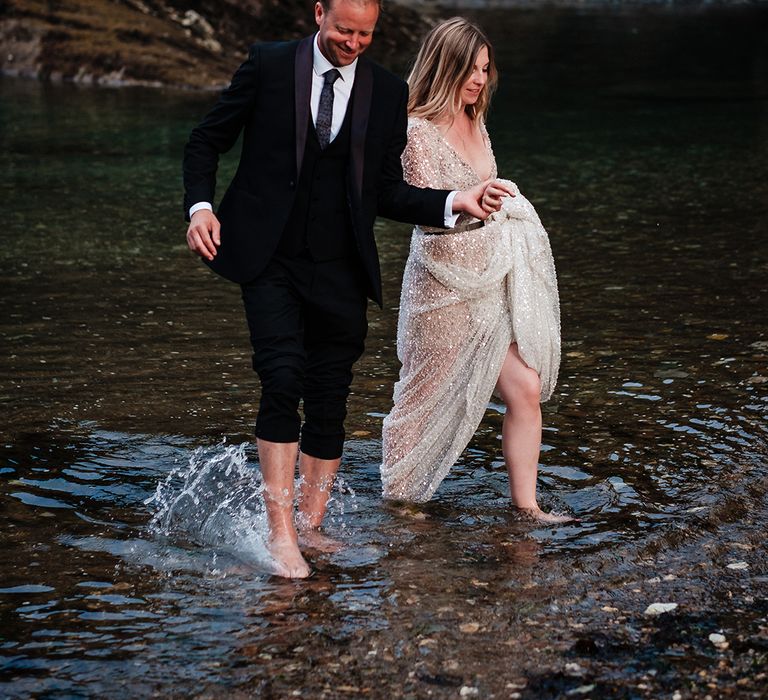 Watermouth Cove wedding with the bride and groom strolling through the sea together at their coastal wedding 