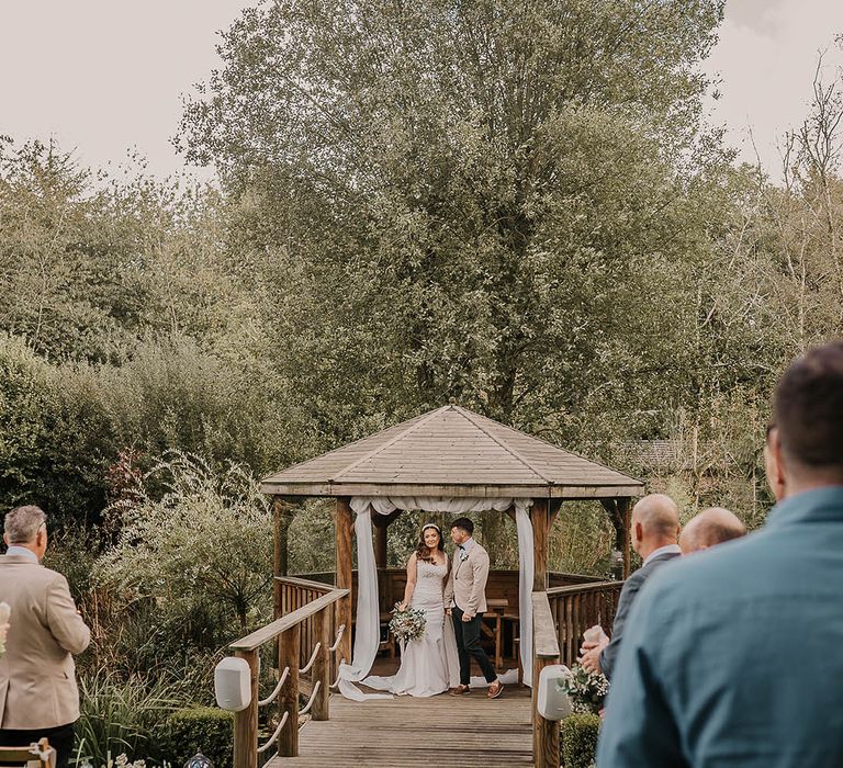 Chycara outdoor wedding venue in Cornwall with the bride and groom stying their vows under the pergola 