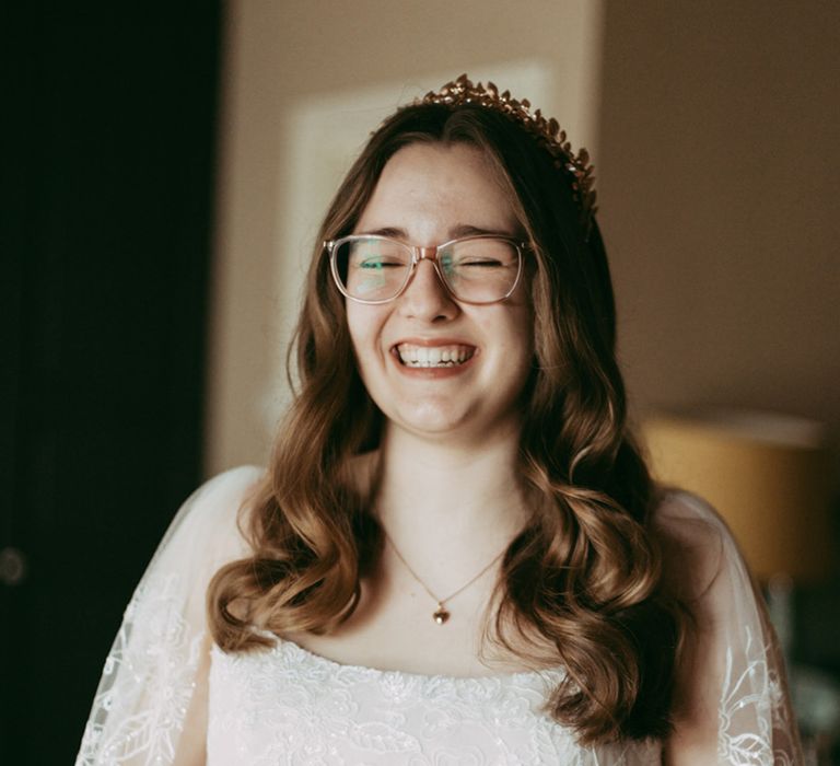 Bride with delicate lace wedding dress from Dress Me Pretty with gold headpiece and glasses 