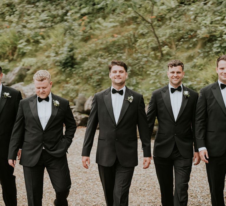 Group wedding party photo of the groom with the groomsmen in black tuxedos 